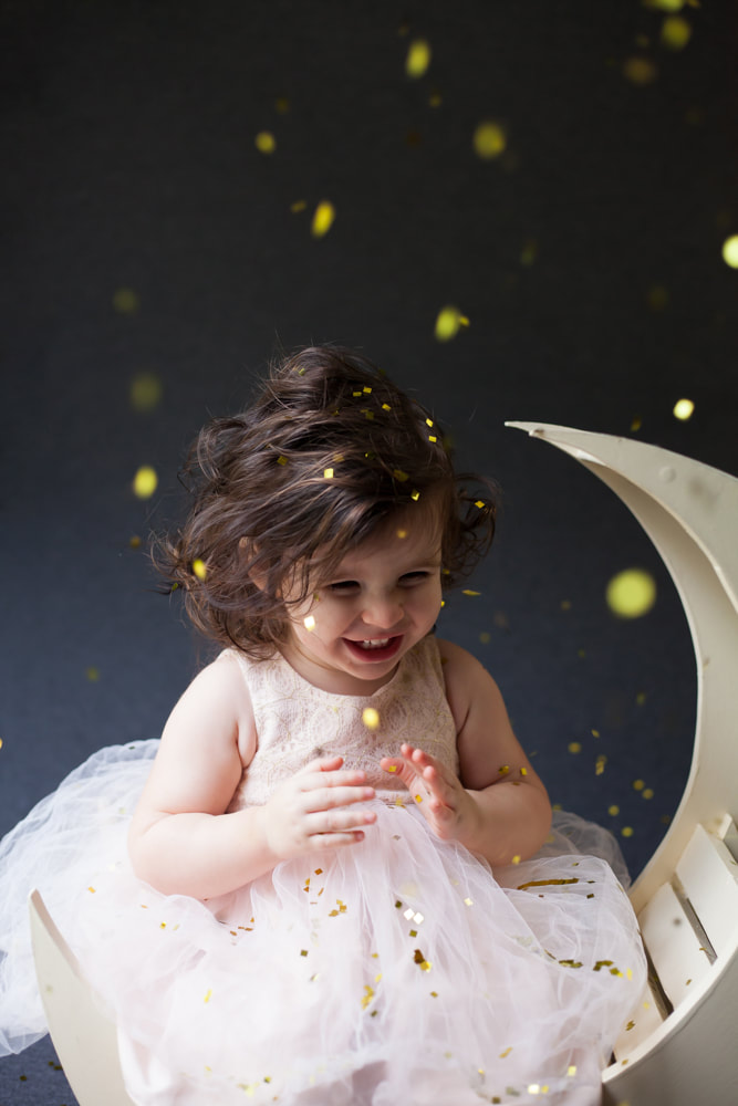 Baby laughs and smiles as confetti falls on her