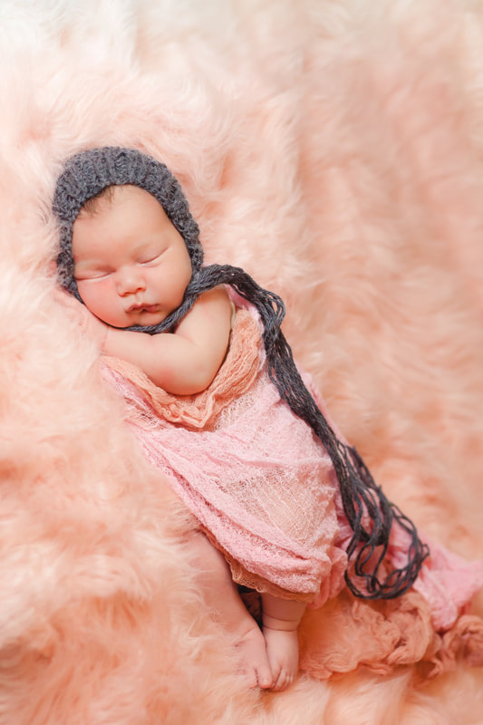newborn baby girl sleeping in a cloud of pink fuzz