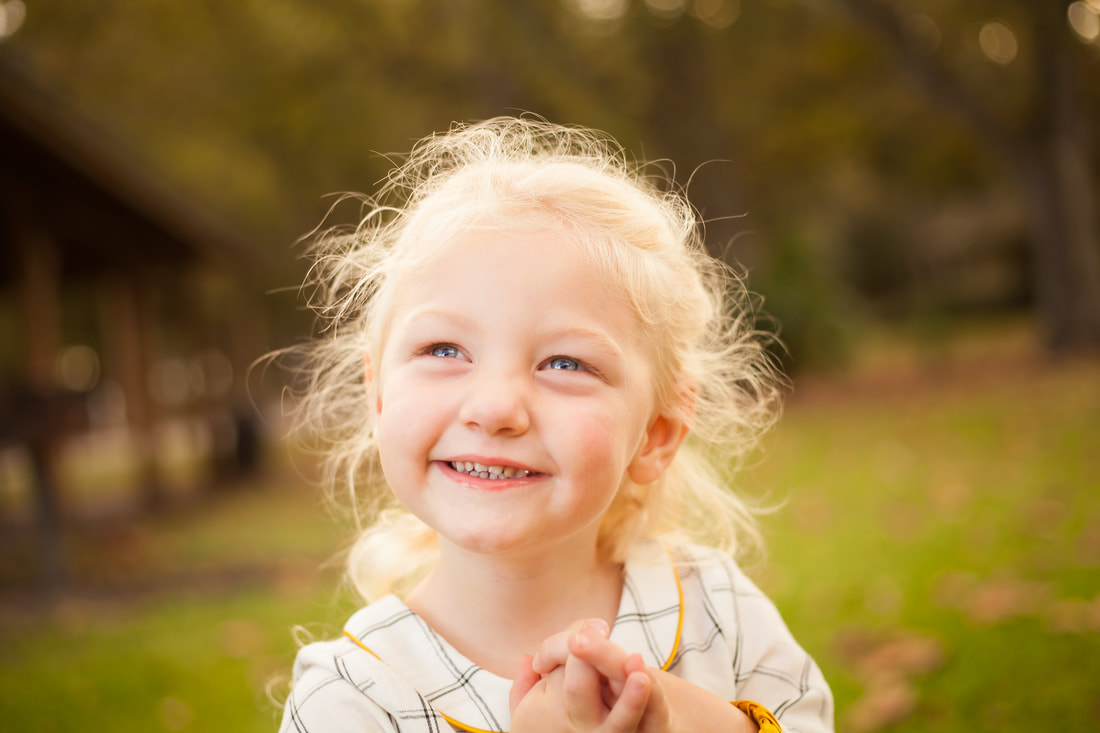Close up of toddler in smiling in a sun drenched field in Lakeland Florida