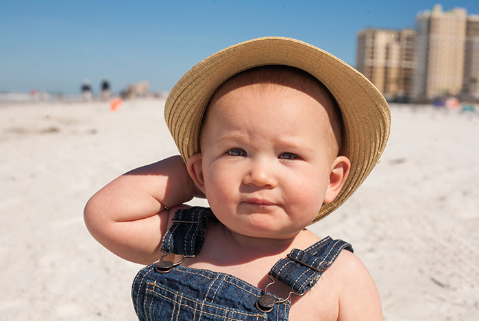 Baby wearing straw hat looks at camera on Clearwater Beach