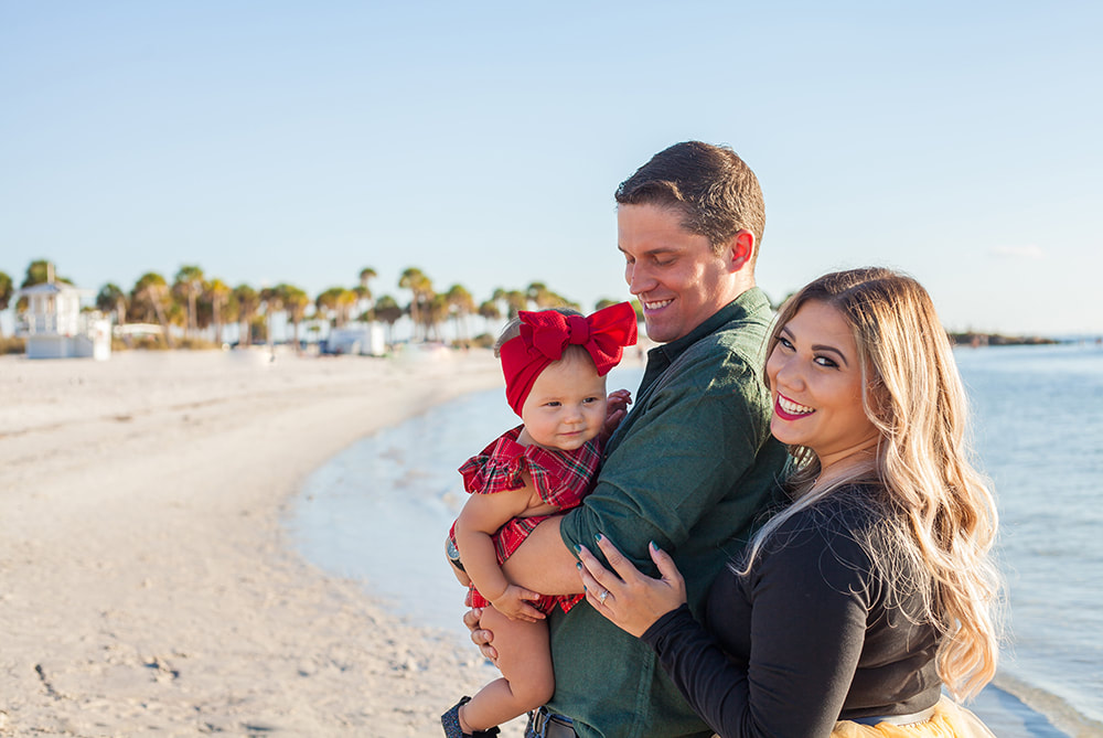 Family of three smiling on the beach in Tarpon Springs, FL
