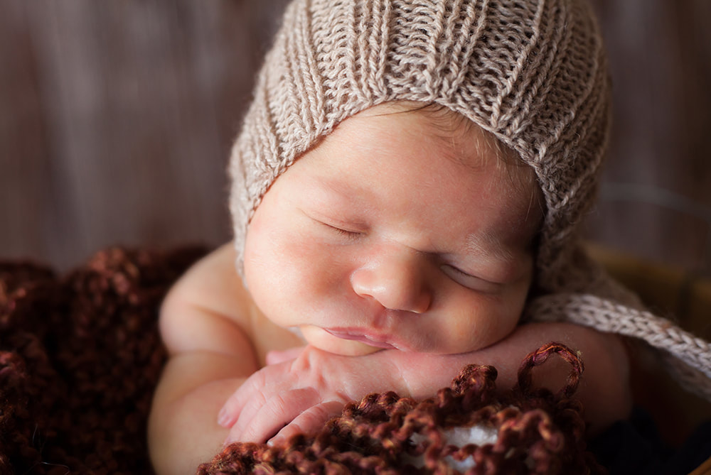 Photograph of newborn baby sleeping with his head on his arms