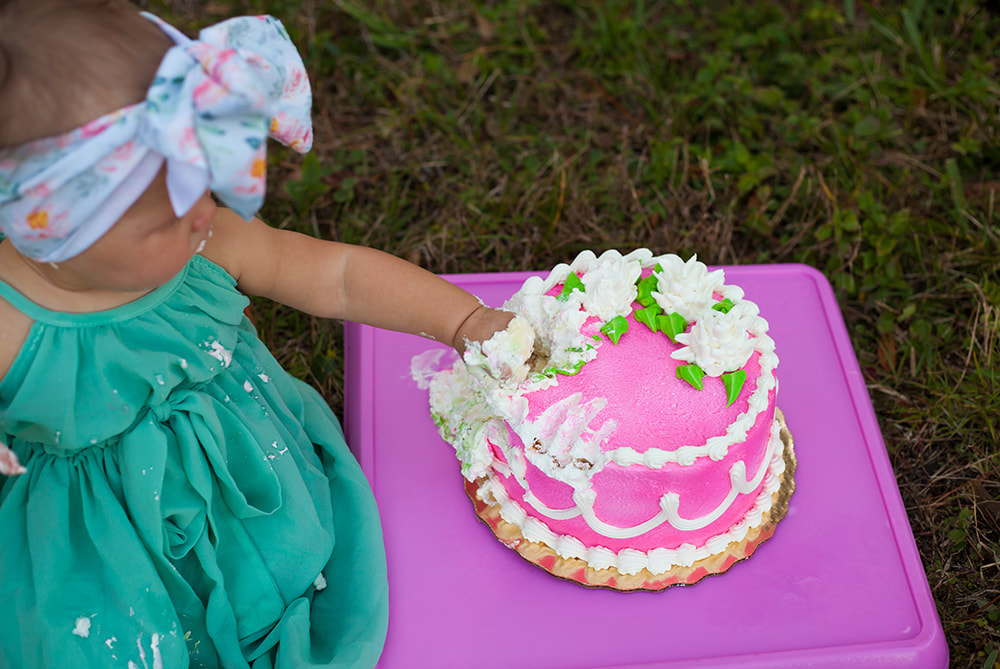 Close up of baby girls hand digging in to pink cake