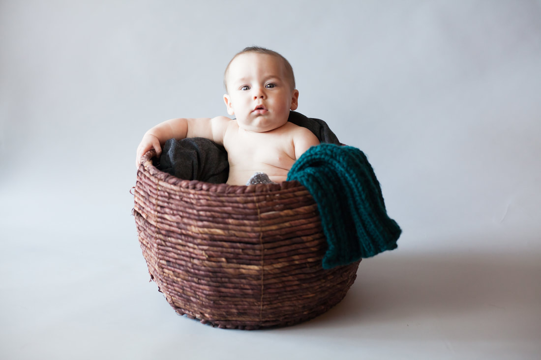 Chunky Baby sits in brown basket on Grey background