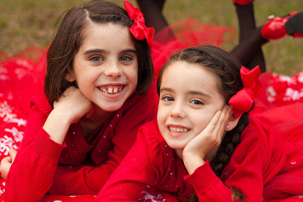 Two girls in red smile at the camera in a park in Floral City FL