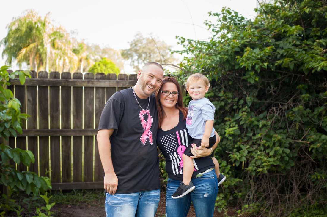 Family of three wearing breast cancer awareness shirts pose together smiling
