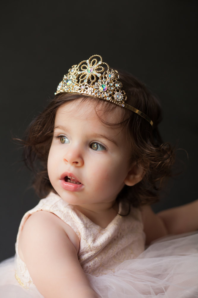 Sweet toddler wearing a tiara looks up off camera