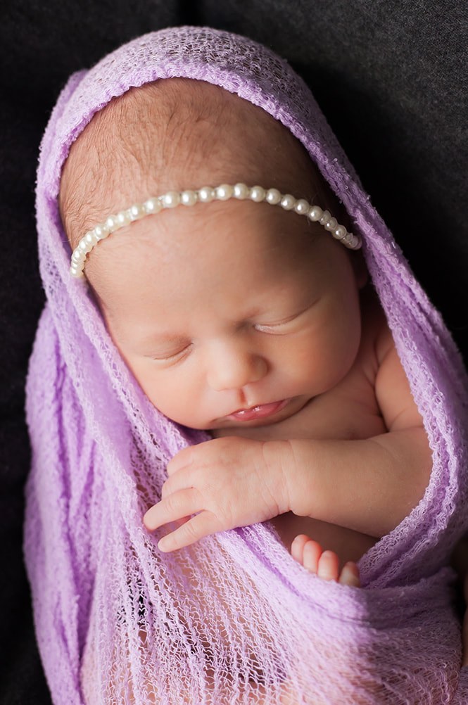 close up of sleeping baby wrapped in a soft cheesecloth swaddle wrap. Photo taken in Wesley Chapel Florida