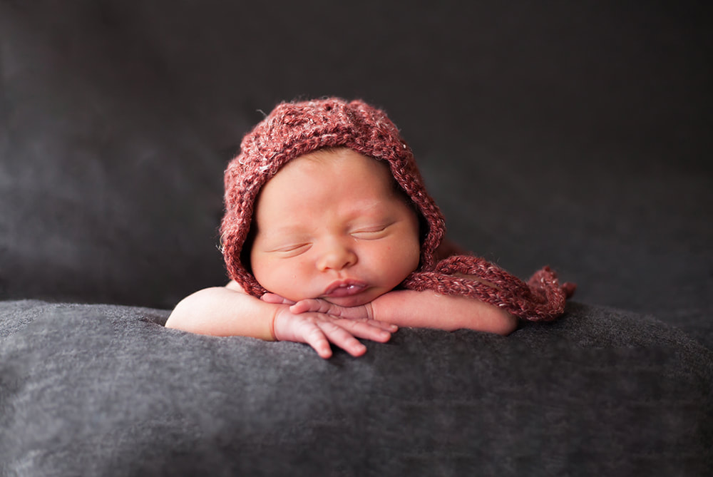 Newborn baby with her head propped on her hands