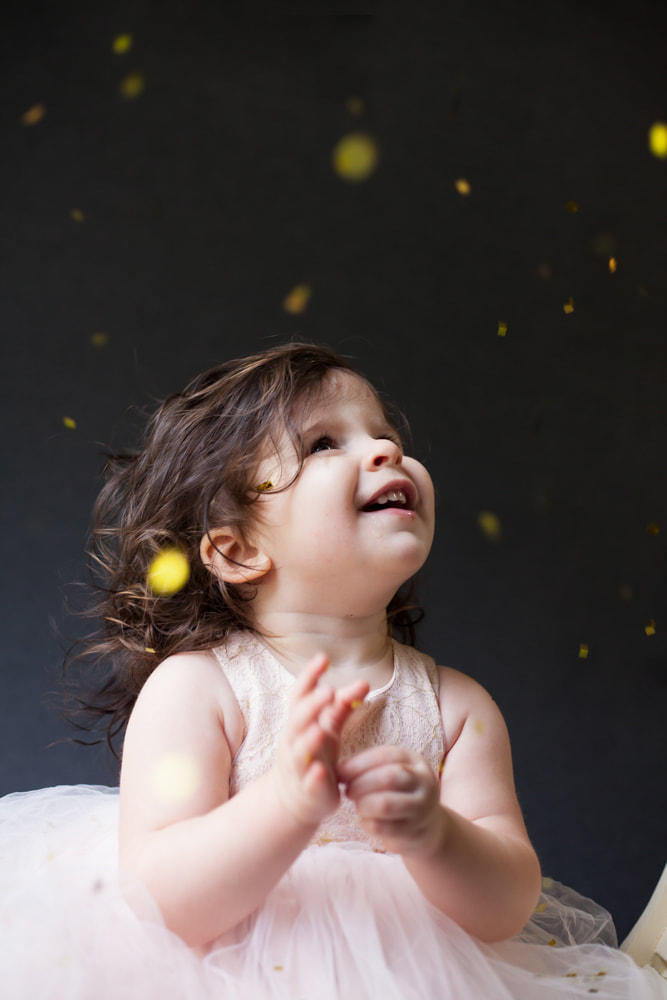 18 month old baby looks up and glitter and confetti falling on her