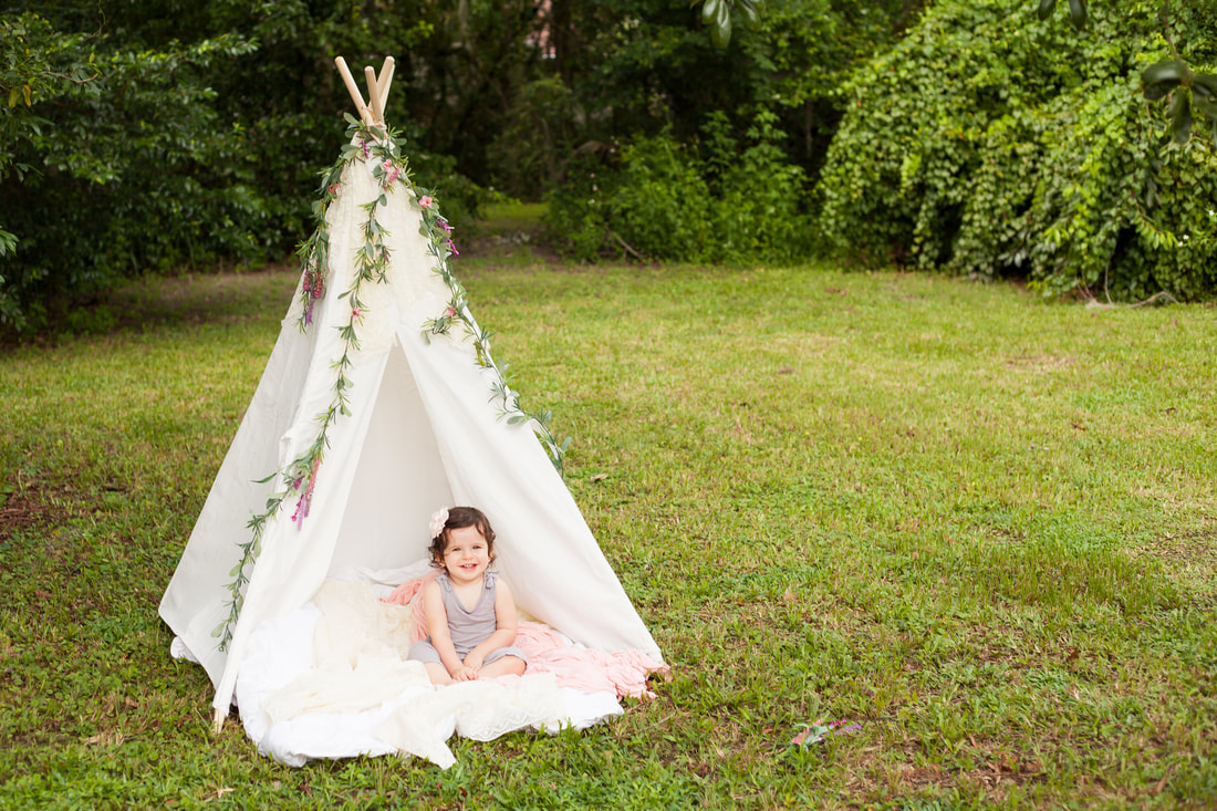 Baby sits in front of white tent in a beautiful field in Odessa FL