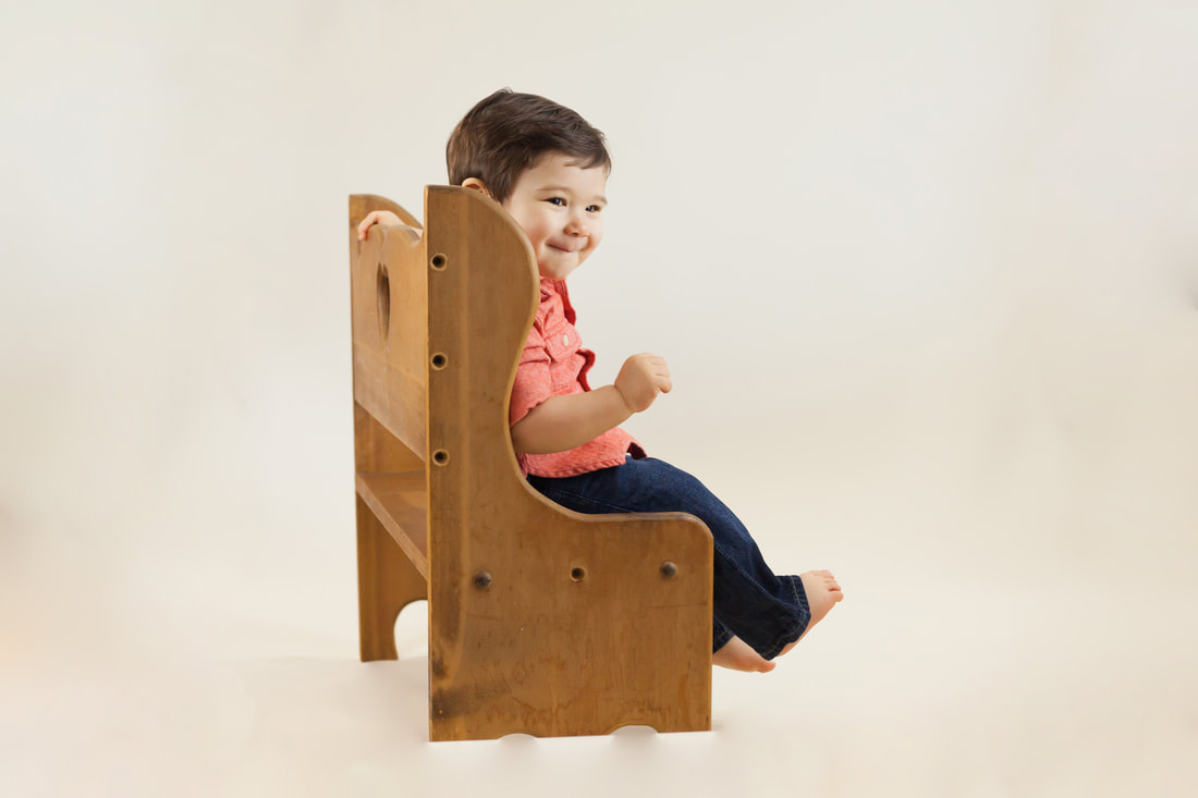 Smiling one year old sitting on wooden bench