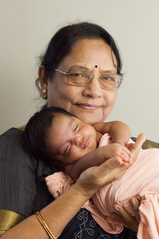 indian grandmother holding her newborn baby granddaughter