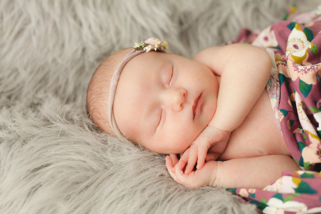 Close up photo of Newborn baby girl in a flower wrap with matching headband