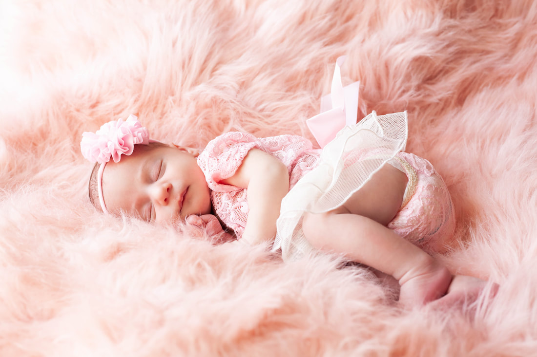 baby girl in pink lace sleeping on her side on pink fur