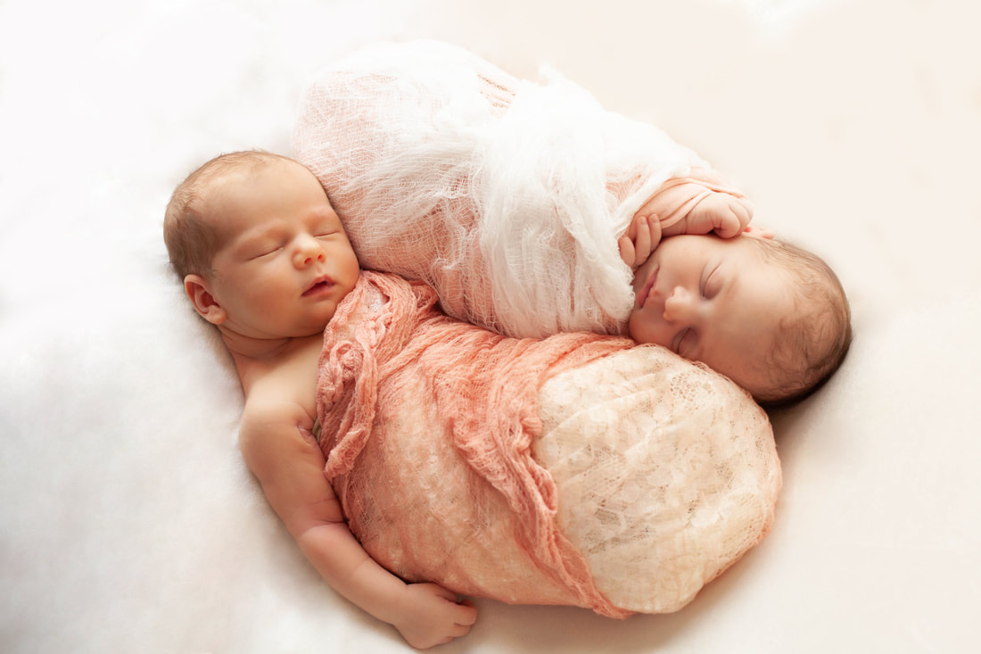 Two swaddled babies in Lace sleeping in a Yin Yang position