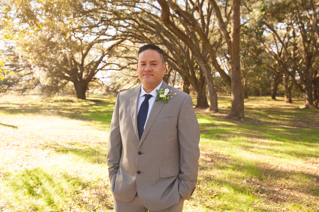 Groom smiles in front of arching trees