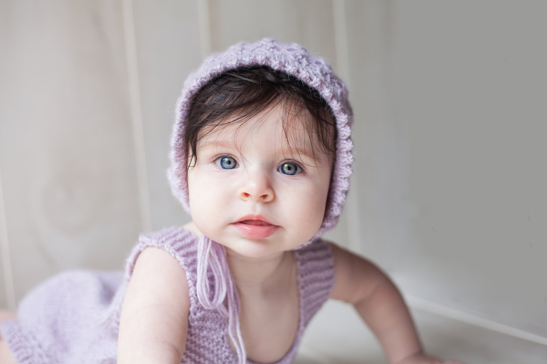 Close up portrait of baby with purple bonnet on