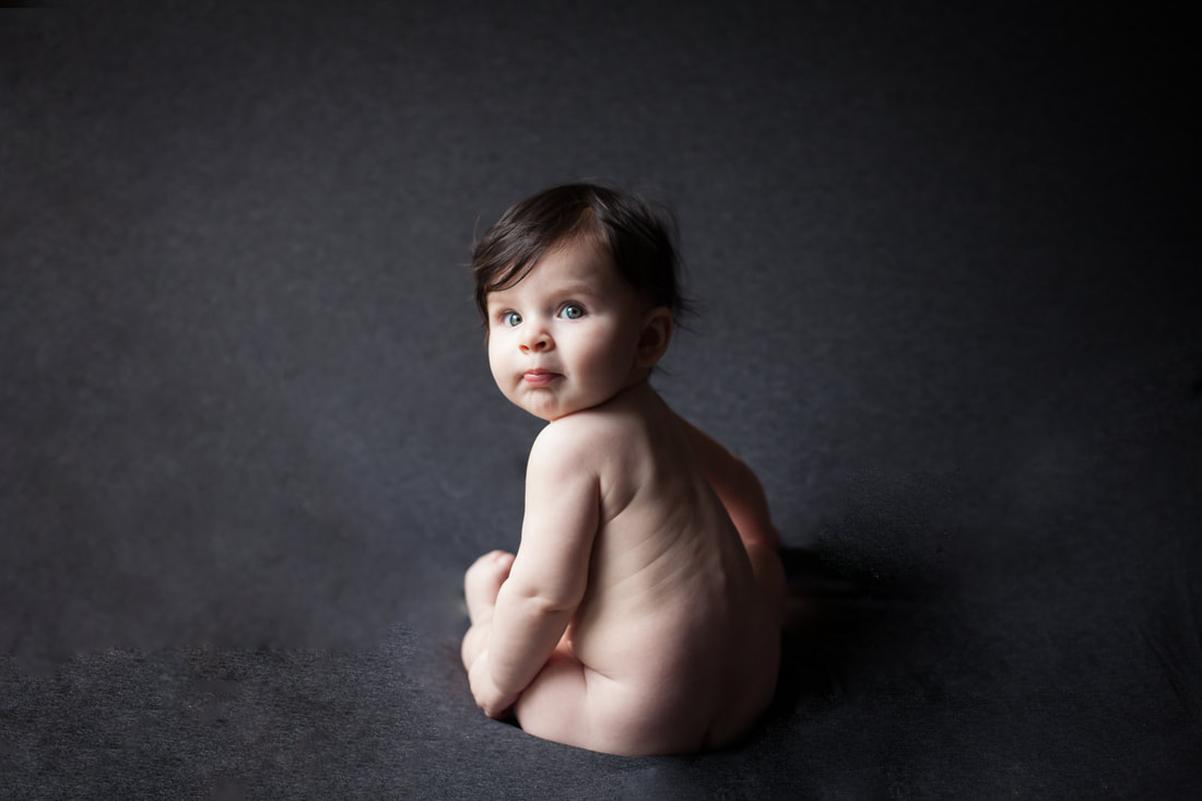 Baby girl looks over her shoulder in studio portrait