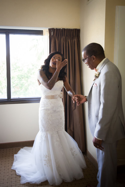 Bride wipes her tears while her father looks at her lovingly