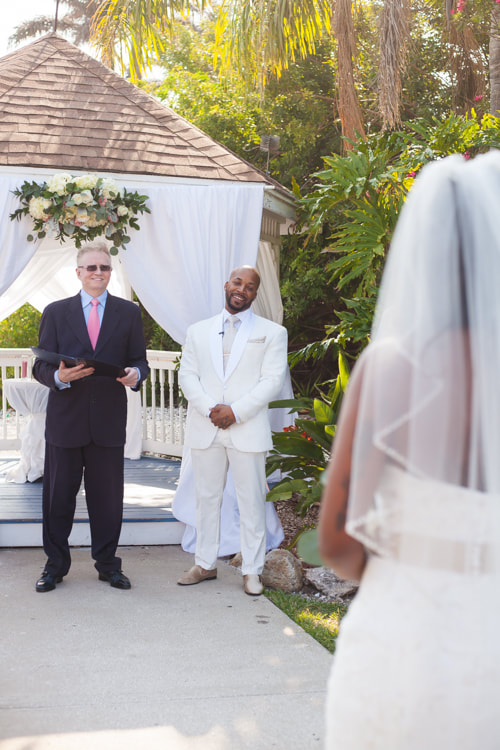 Bride walks towards groom while he smiles at her