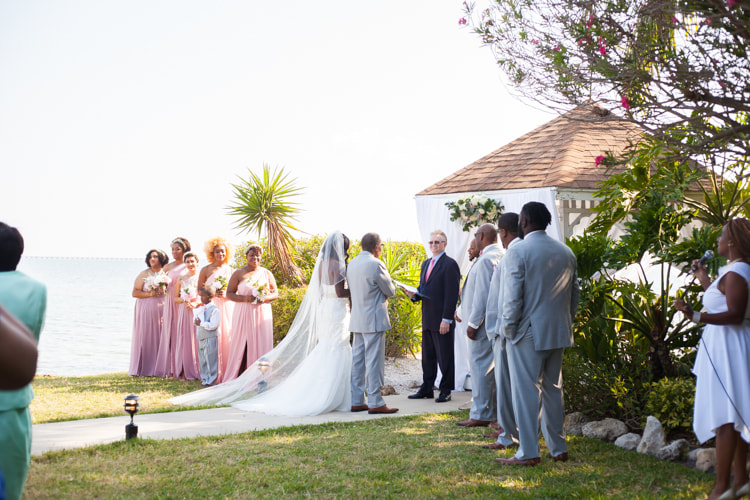 Bride and groom stand at alter flanked by their bridal party at a waterfront gazebo at The Rusty Pelican
