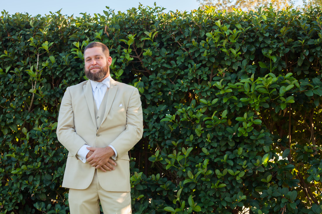 Smiling Groom stands in front of hedge at Citrus Hills Country Club Wedding
