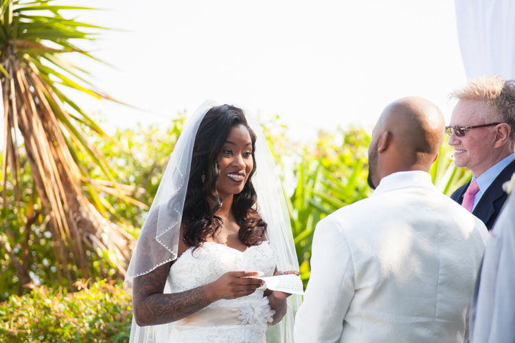 bride smiles at groom while she reads her vows
