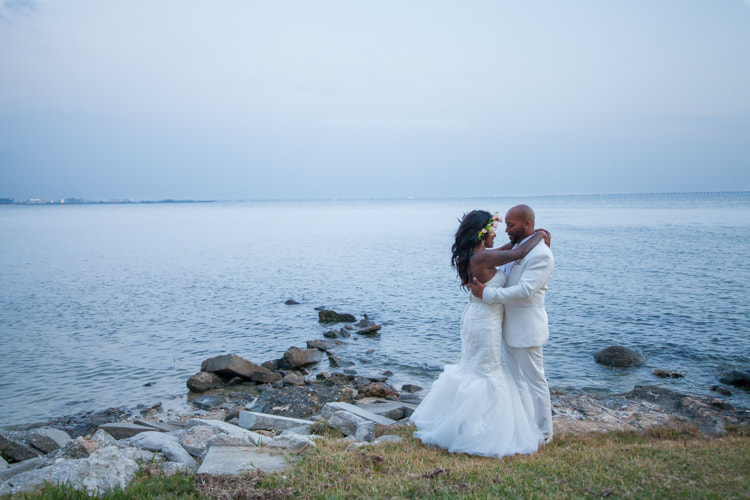 Photograph of bride and groom embracing on the rocky shoreline in Tampa FL