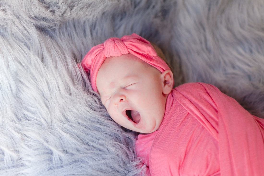 in Lutz a newborn baby swaddled in pink yawning big