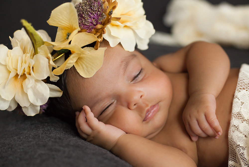 close up of sleeping baby girl with brown skin wearing a crown of flowers