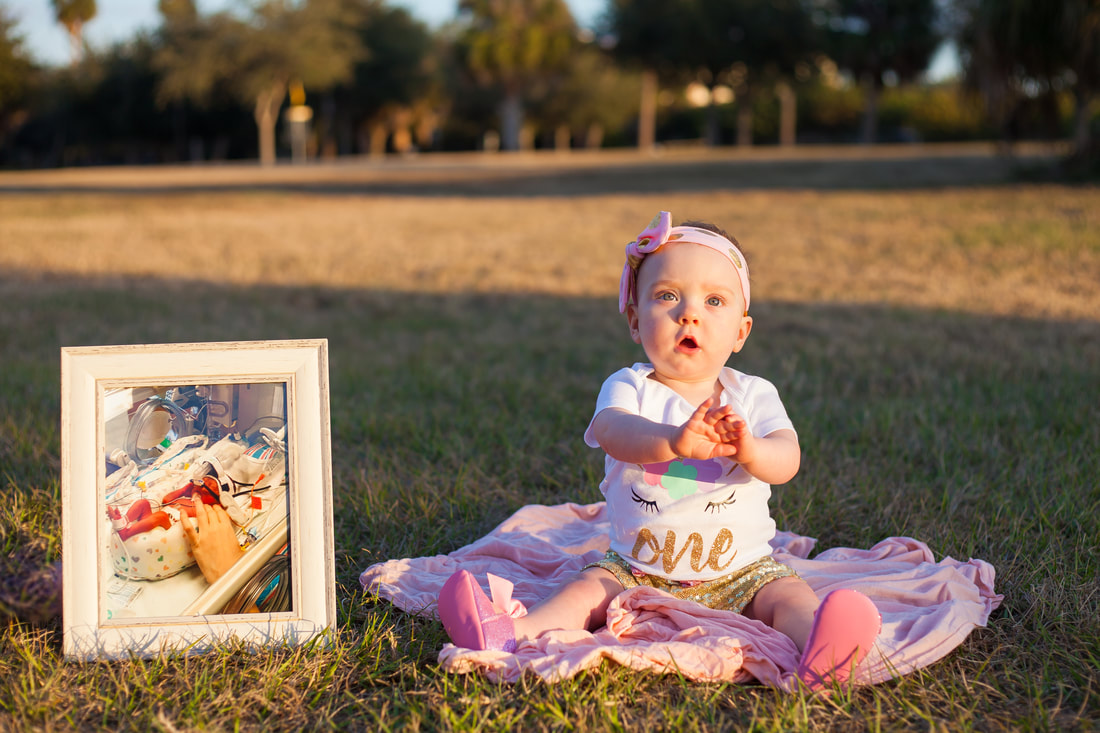 One year old poses with photo of herself in the NICU