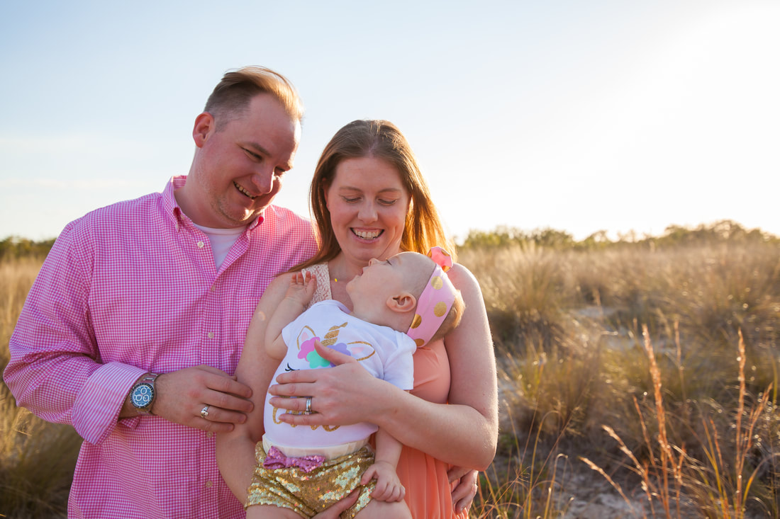 Parents and baby smile at each other in outdoor portrait in tampa FL