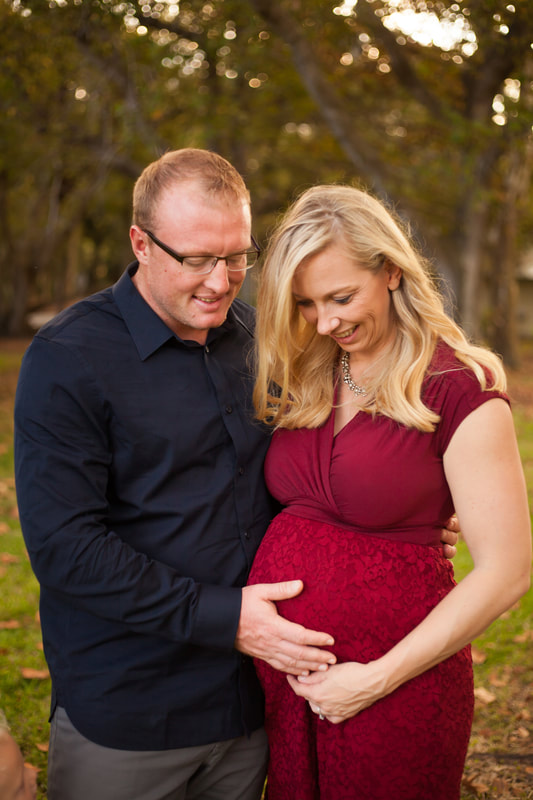 Maternity photo, mother-to-be and husband look down with their hands on the mother's belly 