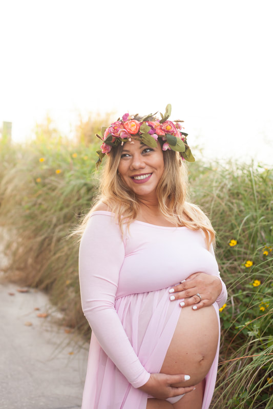 maternity photo of mother smiling off camera wearing a flower crown and pink gown