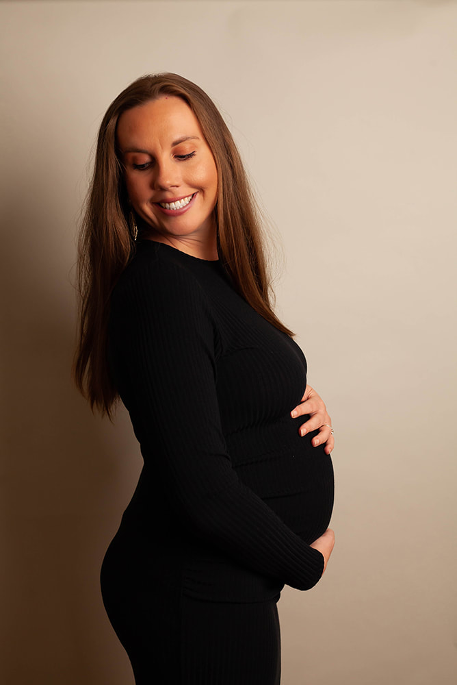 Maternity photo of a woman holding her belly and looking down 