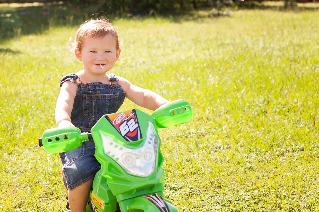 Toddler Boy sits on dirt bike in beautiful sun drenched field in Temple Terrace