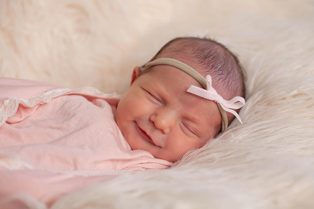 Newborn baby girl smiles in her sleep