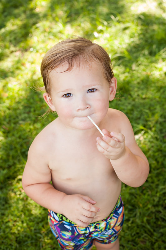 Sweet Toddler looks at camera with lolly pop
