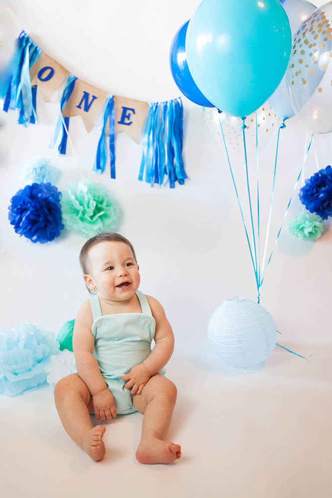 Sweet smiling baby in front of a banner that reads 