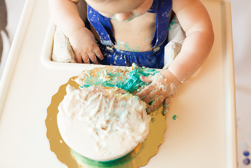 Close up of baby boy smearing birthday cake with his hand