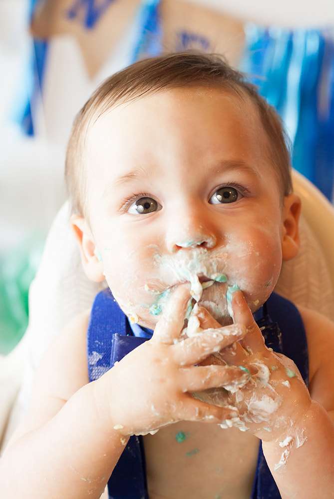 Baby eating cake with icing all over his face