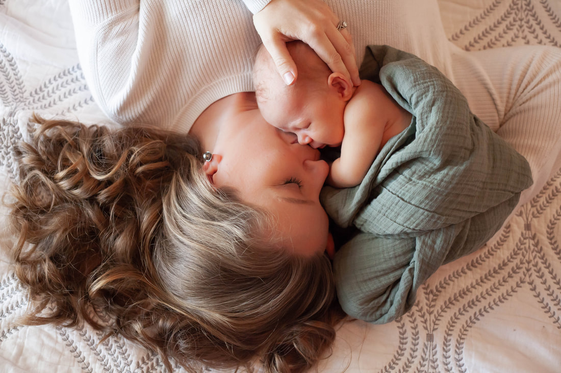 Mother cuddles with her newborn baby son in a bright cheery room