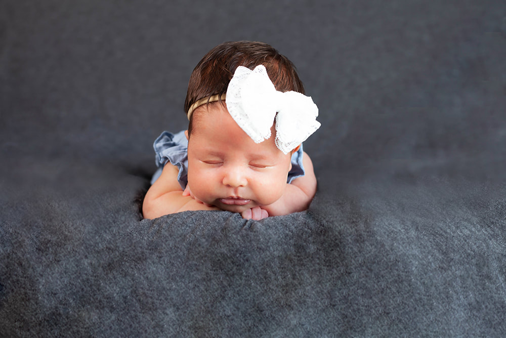 Peacefully sleeping newborn baby girl on tummy facing camera