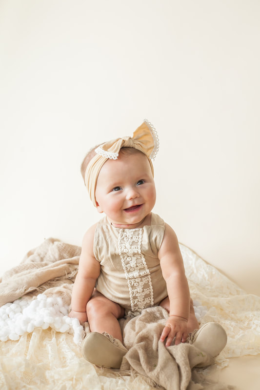 Smiling baby girl photo in off white romper on an off white background