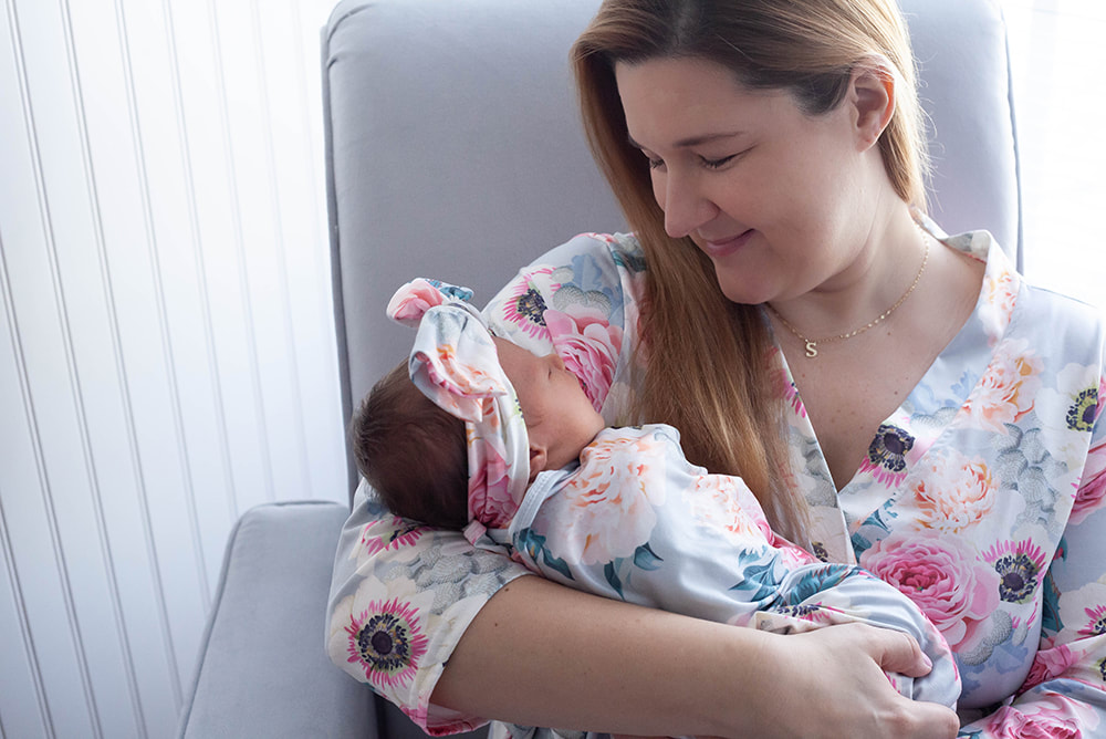 Mother looks lovingly at her newborn daughter in matching outfits