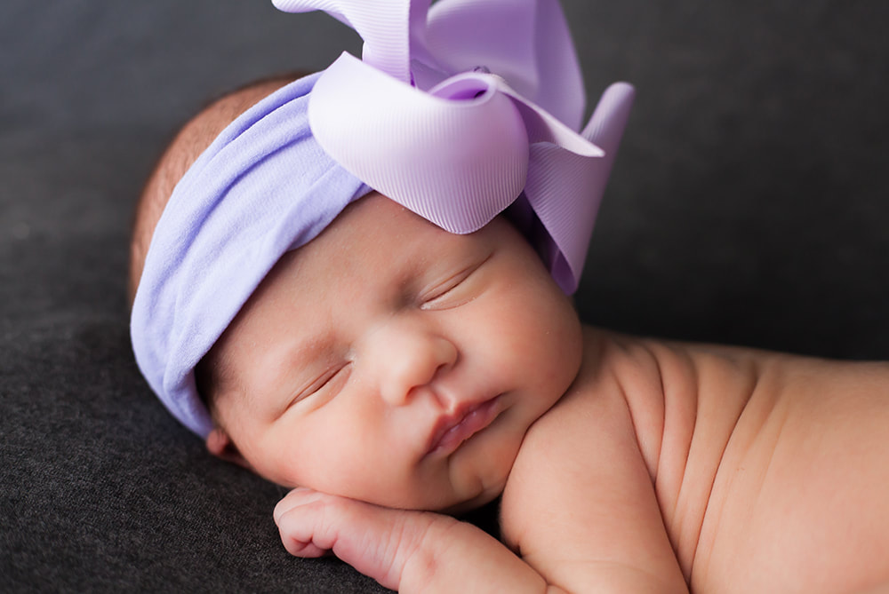 Close up of chunky baby wearing a purple bow in Wesley Chapel, Florida