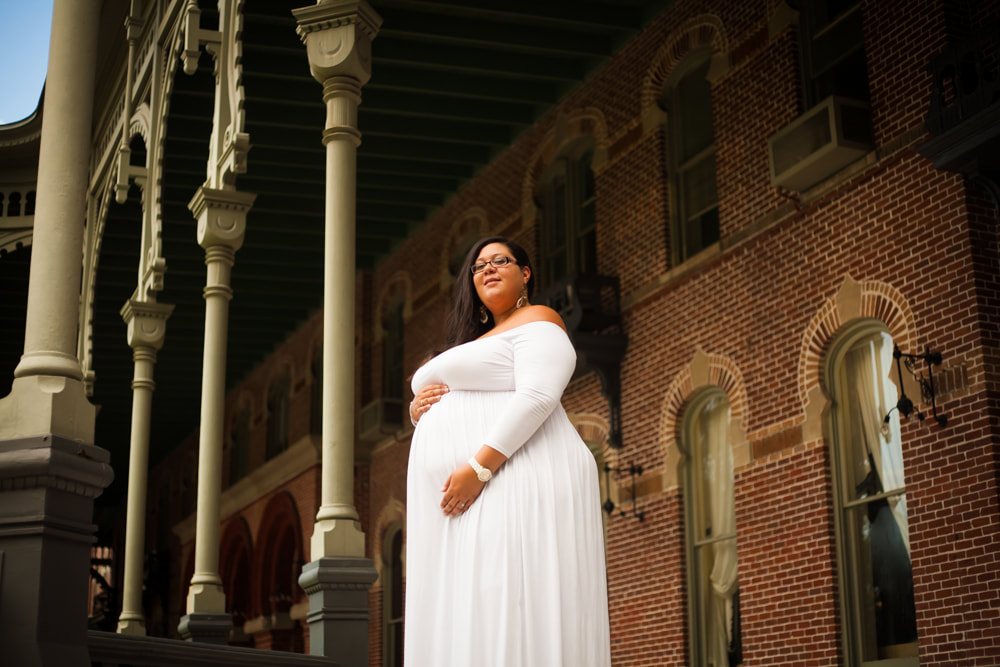 Maternity photo of a pregnant woman standing on an ornate veranda on The University of Tampa campus