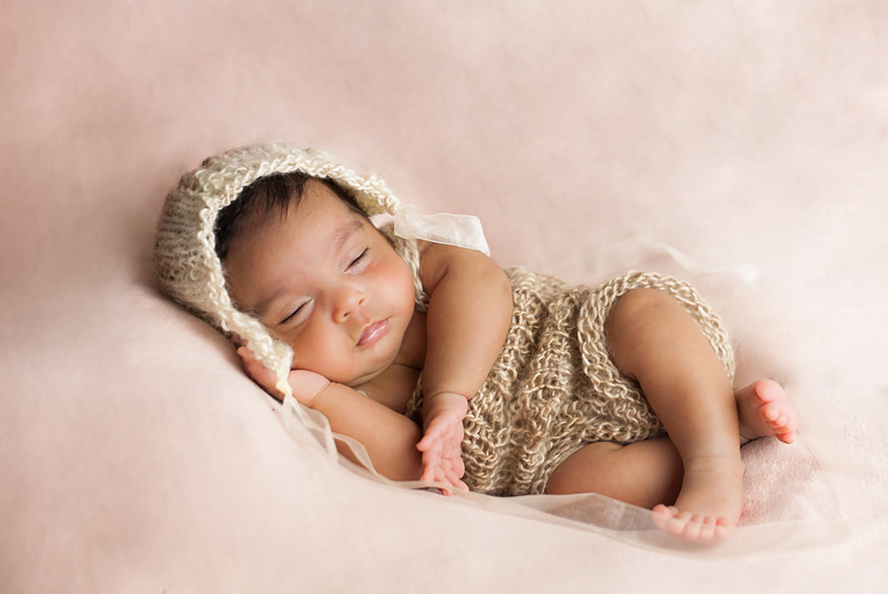 sleeping baby in side lying pose with a brown and pink color scheme 
