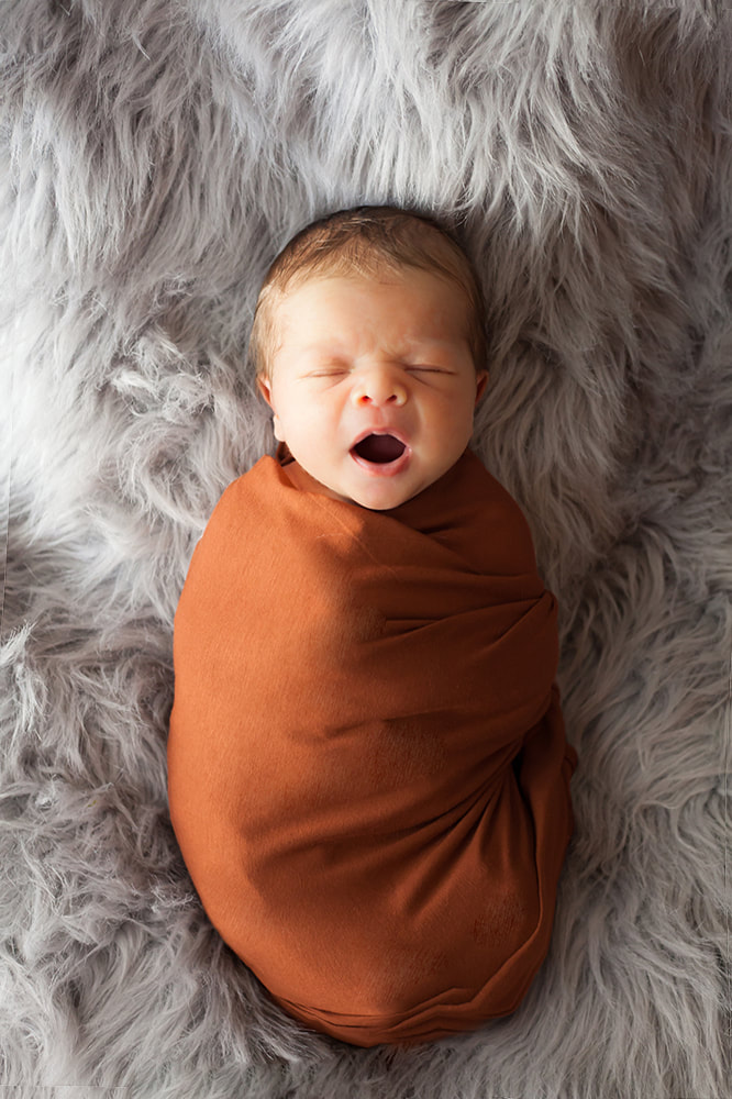 Swaddled Newborn baby yawning
